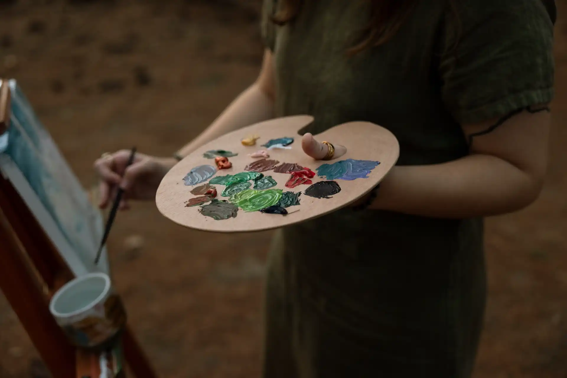 Artist holding a wooden paint palette with vibrant colors while painting outdoors